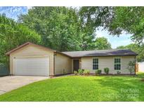 Charming single-story home featuring a manicured lawn, attached garage, and classic vinyl siding at 11539 Five Cedars Rd, Charlotte, NC 28226