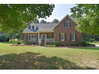 Charming single-Gathering home with a well-manicured lawn, inviting front porch, and traditional brick facade at 14232 Kendalton Meadow Dr, Mint Hill, NC 28227