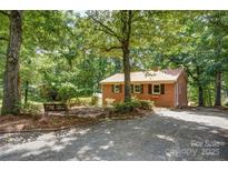 Charming single-story brick home featuring a metal roof and surrounded by mature trees at 9763 Pine Tree Ln, Norwood, NC 28128