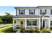 Charming front porch with a yellow door and a welcoming wreath, enhancing the curb appeal of this lovely townhome at 1101 Plaza Walk Dr, Charlotte, NC 28215
