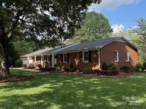 Charming brick home with lush green lawn and mature trees creating a serene outdoor space at 1116 Fieldstone Rd, Mooresville, NC 28115