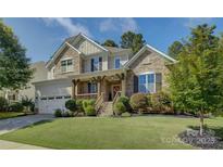 Charming two-story home with stone accents, a wooden porch, and a well-manicured lawn at 17537 Caddy Ct, Charlotte, NC 28278