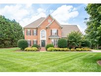 Stately brick home featuring a manicured lawn, mature trees, and meticulously shaped shrubs for enhanced curb appeal at 2019 Heirloom Ct, Matthews, NC 28104