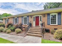 Inviting brick home featuring a red front door, blue shutters, and well-maintained landscaping at 3304 Chilham Pl, Charlotte, NC 28226