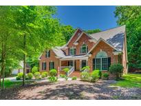 Traditional brick home boasts mature landscaping and a welcoming front porch at 413 Farm Branch Dr, Fort Mill, SC 29715