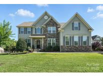 Inviting two-story home with a stone facade, gray siding, and well-manicured landscaping at 8427 Penton Pl, Harrisburg, NC 28075