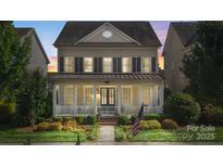 Charming two-story home featuring a welcoming front porch and well-manicured lawn at 11806 Stirling Field Dr, Pineville, NC 28134