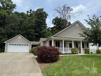 Charming home featuring manicured lawn, mature landscaping, and inviting front porch with classic columns at 156 Tarrington Dr, Statesville, NC 28625