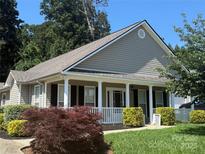 Charming single-story home with a covered front porch, manicured lawn, and mature trees at 156 Tarrington Dr, Statesville, NC 28625