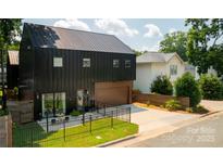 Modern black home with metal roof, garage, fenced yard, and patio seating area at 2107 W Trade St, Charlotte, NC 28216