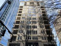 Exterior shot of a tall beige apartment building with balconies next to a blue glass building in a city at 230 S Tryon St # 304, Charlotte, NC 28202