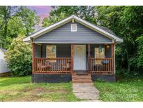 Charming bungalow with a covered porch, chairs, and lush landscaping at 2312 Tate St, Charlotte, NC 28216