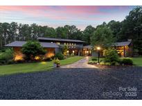 Beautiful exterior view of modern home with manicured lawn and mature trees at twilight at 307 E Allenton St, Mount Gilead, NC 27306