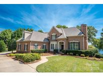 Stately brick home featuring a manicured lawn and mature landscaping under a blue sky at 3996 Channel Point Ln, Denver, NC 28037