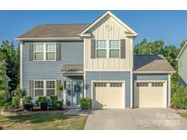 Charming two-story home with a three car garage, light blue siding and a welcoming front porch at 4113 Bent Green Ln, Monroe, NC 28112
