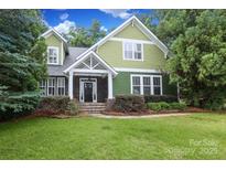 Charming two-story green home with a stone-accented front porch and lush landscaping at 458 Leaf Arbor Ct, Clover, SC 29710