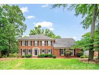 Beautiful two-story brick home with lush green lawn and mature trees at 10918 Megwood Dr, Charlotte, NC 28277