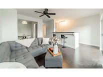 Bright living room with a ceiling fan, grey couch, dark floors, and a stylish breakfast bar at 1315 East Blvd # 327, Charlotte, NC 28203