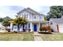 Charming two-story home featuring a blue front door, well-manicured lawn, and beautiful landscaping at 15280 Leslie Brook Rd, Huntersville, NC 28078
