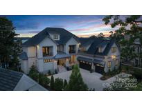 Stunning lakefront home featuring a three-car garage, black framed windows, and covered entryway at 18007 Harbor Light Blvd, Cornelius, NC 28031