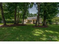 Charming home nestled among mature trees with lush green lawn and manicured landscaping at 1801 Teddington Dr, Charlotte, NC 28214