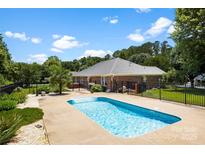 Backyard oasis featuring a sparkling pool, mature trees, and black aluminum fence at 1958 Cameron Heights Cir, Denver, NC 28037