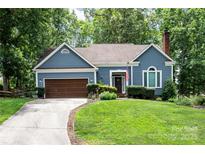 Charming single-story home featuring a manicured lawn, blue siding, and an attached two-car garage at 2133 Highland View Ln, Charlotte, NC 28214