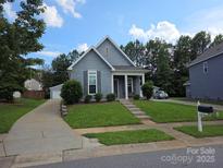Charming blue home with a well-manicured lawn, inviting front porch, and detached garage at 4032 Wilgrove Way Dr # 252, Charlotte, NC 28213