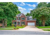 Charming two-story brick home with green shutters, attached garage, and manicured lawn at 6016 Graburns Ford Dr, Charlotte, NC 28269
