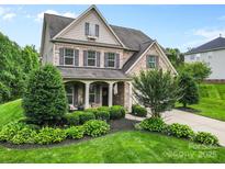 Beautiful brick two-story home featuring a covered porch, shutters, and well-maintained landscaping at 9801 Blackbird Hill Ln, Mint Hill, NC 28227