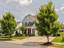 Beautiful two-story home with a well-manicured lawn, mature trees, and a welcoming front porch at 1009 Hampton Grove Rd, Waxhaw, NC 28173