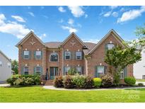 Beautiful brick home with lush landscaping and green shutters under a bright blue sky at 1009 Murandy Ln, Matthews, NC 28104