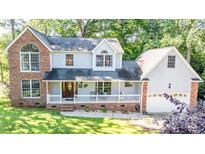 Charming two-story home with brick accents, a front porch with white railings and manicured lawn and mature landscaping at 110 Club Dr, Mooresville, NC 28115
