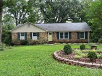Charming brick ranch-style home with a lush green lawn and well-manicured garden featuring a delightful bird bath at 11329 Torino Rd, Matthews, NC 28105