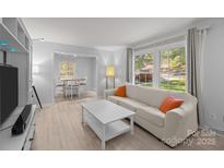 Bright living room featuring a large window and connecting dining area, perfect for entertaining at 11329 Torino Rd, Matthews, NC 28105