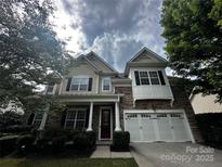 Charming two-story home featuring a stone facade, attached garage, and manicured landscaping at 1386 Secret Path Dr, Fort Mill, SC 29708