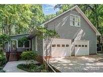 Charming home featuring an attached two-car garage, beautiful trees, and well-maintained landscaping at 140 Rustic Way Ln, Mooresville, NC 28117