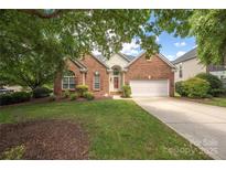 Charming brick home with mature trees, landscaped yard, and a two-car garage on a sunny day at 14103 Hiawatha Ct, Huntersville, NC 28078