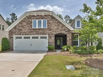 Charming stone and siding home with a two-car garage and inviting front yard at 15614 Aviary Orchard Way, Charlotte, NC 28278