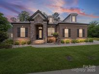 Charming brick home featuring a stone facade entrance, manicured lawn and lush landscaping at 217 Turtleback Rdg, Weddington, NC 28104