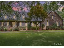 Charming brick home featuring a well-manicured lawn and inviting front porch, set beneath a colorful dusk sky at 394 E Goldmine Rd, Wadesboro, NC 28170