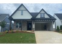 Charming two-story home featuring a stone facade, open garage, and a well-manicured lawn at 5578 Caneel Ln # 1227, Denver, NC 28037