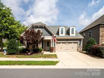 Charming home featuring a two-car garage,dormer windows, and a manicured lawn with mature tree at 741 Garrett Green Way # 64, Fort Mill, SC 29715