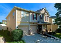 Charming two-story home featuring a two-car garage and welcoming front porch with stone accents at 107 Ameena Chase Trl, Mooresville, NC 28117