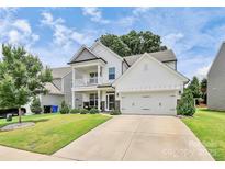 Beautiful two-story home featuring a front porch, a two-car garage, and a well-manicured lawn at 139 Suggs Mill Dr, Mooresville, NC 28115