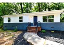 Charming renovated ranch-style home featuring a white exterior with a blue brick foundation and black door at 1513 Greenview Pl, Charlotte, NC 28208