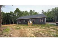 Charming single-story home with a inviting front entrance, complemented by a dark siding and red shutters at 1870 Hwy 49 None, New London, NC 28127