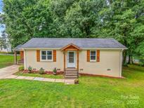 Charming single-story home showcasing a well-maintained front lawn and inviting front entrance with wood accents at 21322 Mccall St, Cornelius, NC 28031