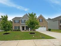 Charming brick two-story home featuring a manicured lawn, inviting front porch, and attached two-car garage at 2382 Drake Mill Sw Ln, Concord, NC 28025