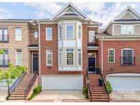 Charming brick townhome featuring an attached two-car garage and lovely front entrance with decorative windows at 3036 Luke Crossing Dr, Charlotte, NC 28226